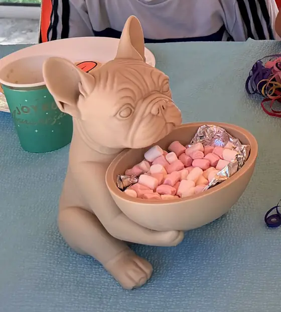 Kucağında şekerlerle dolu kase tutan pembe bulldog figürü